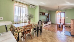 A dining area with a table and chairs, a potted plant, and a kitchen area with cabinets and a microwave.