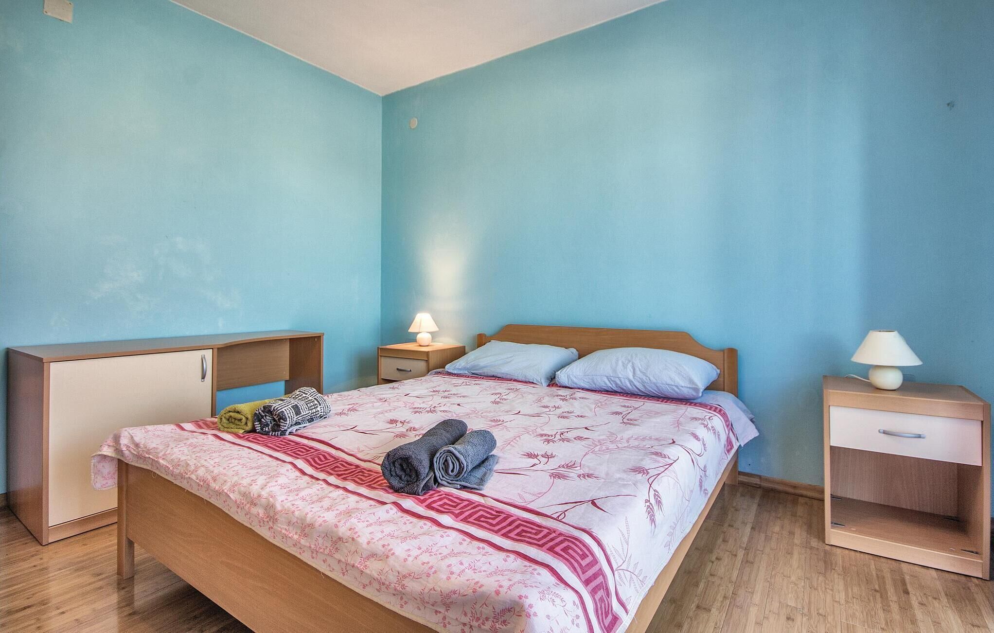 Ein Schlafzimmer mit Bett, Nachttischen, einem Kleiderschrank und einer Lampe.