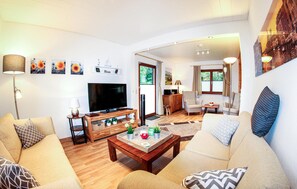 Relax in this stylish living room with a flat-screen TV, comfortable sofa, and wooden coffee table.