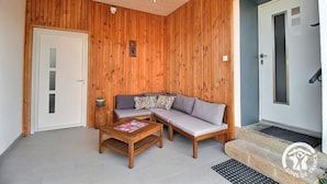 Et værelse med træpaneler, en sofa, et lille bord og en dør.