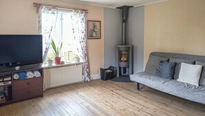 A living room with a television, sofa, fireplace, and potted plants. - Nice home in Munkedal with lake view (Munkedal)