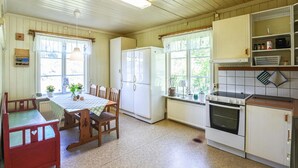 A kitchen with a dining table, chairs, a refrigerator, an oven, and a window with curtains. - Nice home in Munkedal with lake view (Munkedal)
