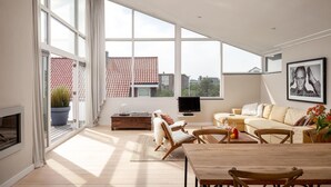 A spacious living room with large windows, a flat-screen TV, a fireplace, and a cozy seating area. - Awesome home in Bergen aan Zee (Bergen aan Zee)