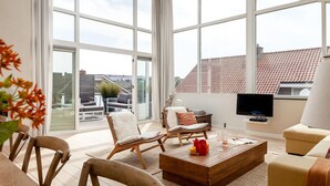A spacious living room with large windows, a flat-screen TV, and a cozy seating area. - Awesome home in Bergen aan Zee (Bergen aan Zee)