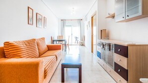 A modern living room with a sofa, a coffee table, and a kitchen area with cabinets and a countertop. - Gorgeous apartment in Cabanes with swimming pool (Cabanes)