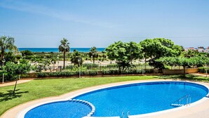A swimming pool with a view of the ocean and a landscaped area with trees and a fence. - Gorgeous apartment in Cabanes with swimming pool (Cabanes)