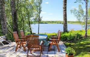 Un espace extérieur aménagé avec des chaises et une table en bois, offrant une vue sur un lac.