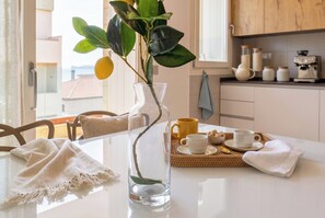A dining table with a clear vase, a yellow mug, and a white cup on a woven tray.