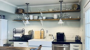 Une cuisine moderne avec des étagères en bois, un réfrigérateur en acier inoxydable et un coin repas comprenant une table et des chaises en bois.