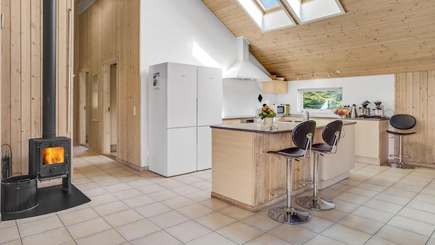 Een moderne keuken met een centraal eiland, een houtkachel en een groot dakvenster.