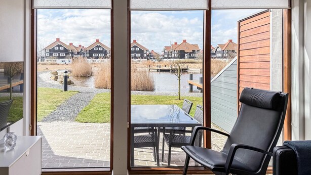 Une pièce avec vue sur un canal, des maisons et une terrasse en bois.
