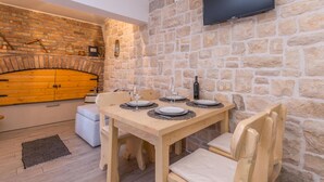 Un comedor acogedor con pared de piedra, una mesa de madera dispuesta para cuatro personas y un televisor montado arriba.