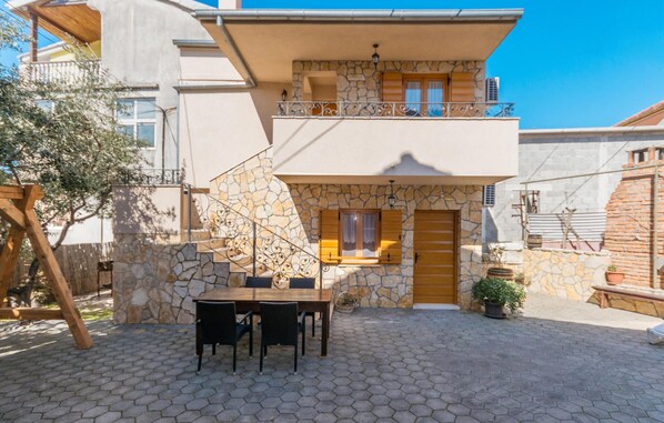 Ein zweistöckiges Gebäude mit einer Stein-Fassade, einem Balkon mit Metallgeländern und einer Holztür.