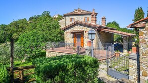 A stone building with a tiled roof, a wooden door, and a small balcony with a metal railing. - Gorgeous home in Arezzo (Arezzo)