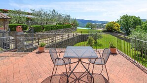 A patio with a table and chairs, a stone wall, and a view of a green landscape and mountains. - Gorgeous home in Arezzo (Arezzo)