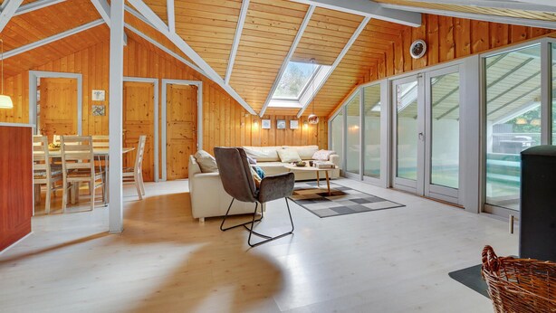 A spacious room with a high ceiling, wooden walls, a skylight, a sofa, a dining table, and large windows. - Beautiful home in Sydals with sauna (Sydals)