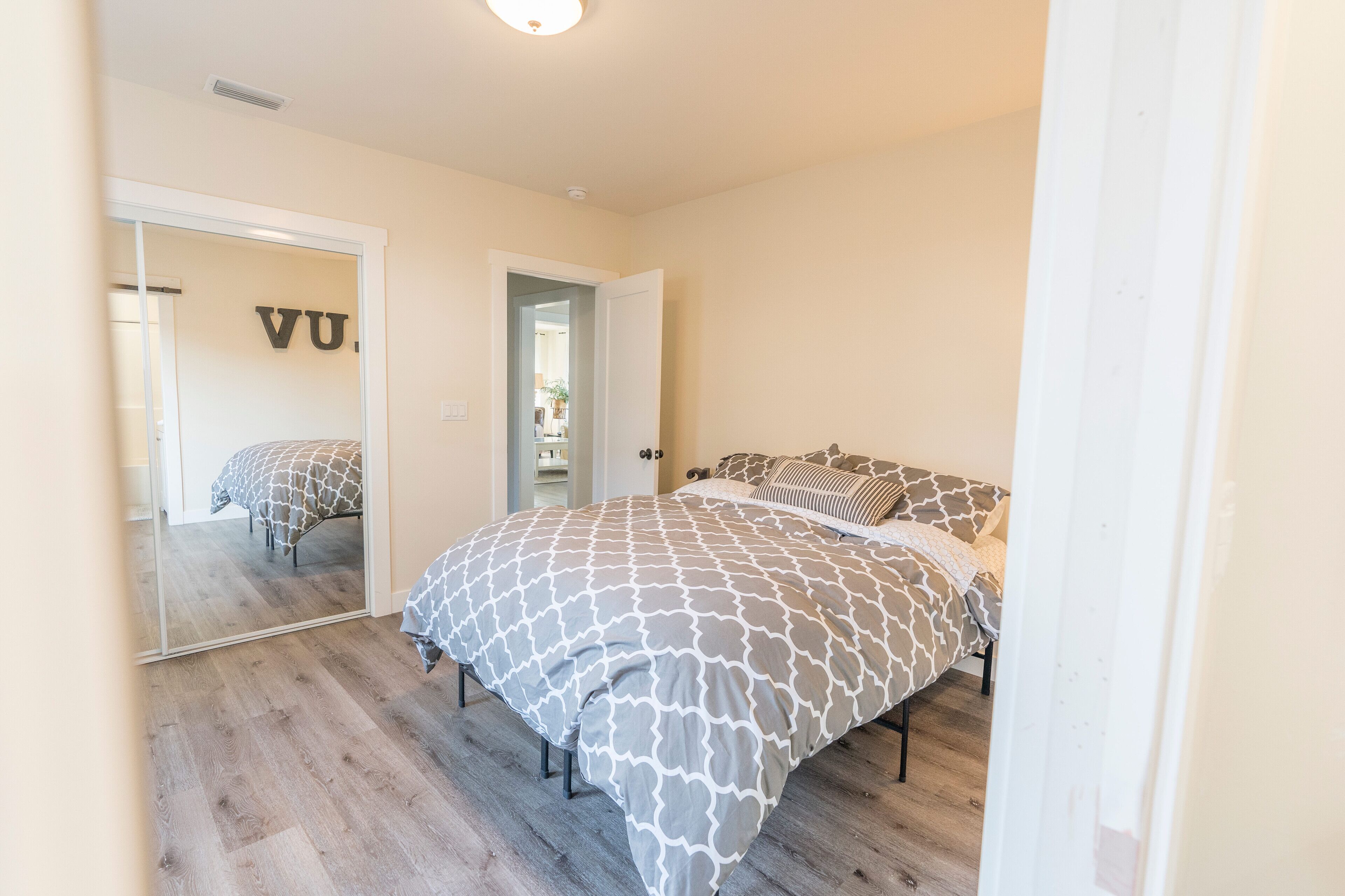 A bedroom with a bed, a mirror, and a door.