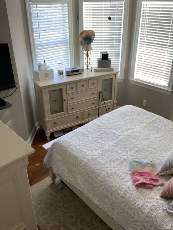 Une chambre à coucher avec un lit, une commode et des fenêtres équipées de stores.