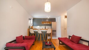 A compact living space with a kitchenette, two red sofas, a small table, and a hanging light fixture. - Amazing apartment in Stari Grad with WiFi (Stari Grad)