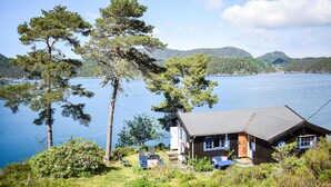 Eine Hütte am See mit Blick auf Wasser und Hügel.
