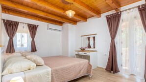 A bedroom with a bed, bedside table, lamp, dresser, mirror, and curtains. - Beautiful home in Rojnici (Rojnici)