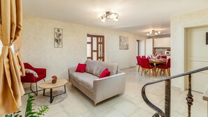 A spacious living area with a sofa, red chairs, a dining table, and a staircase. - Beautiful home in Rojnici (Rojnici)
