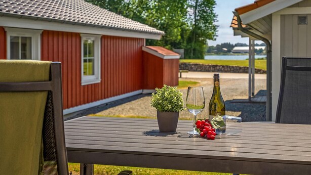Een houten tafel met een bloempot, een fles wijn en een glas.