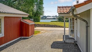 Een grindpad dat leidt naar een rode schuur en een wit gebouw met een pannendak.