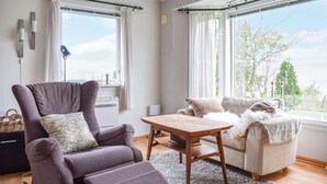 A modern living room with a grey armchair, a beige sofa, and a wooden coffee table. - Cozy home in Aksdal with house sea view (Aksdal)