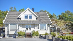 A two-story house with a gabled roof, a front porch, and a stone pathway leading to the entrance. - Cozy home in Aksdal with house sea view (Aksdal)