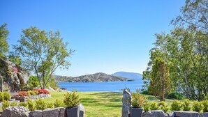 A scenic view of a coastal landscape with a clear sky, a grassy area, and a body of water. - Cozy home in Aksdal with house sea view (Aksdal)