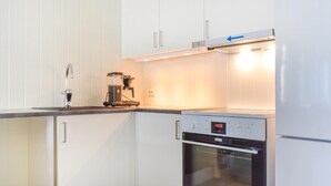 Een compacte keuken met witte kastjes, een koffiezetapparaat en een fornuis.