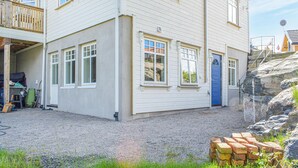Een gebouw met twee verdiepingen, een veranda, een blauwe deur en een grindpad.