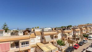 A residential area with terracotta-tiled buildings, balconies, and a clear blue sky.