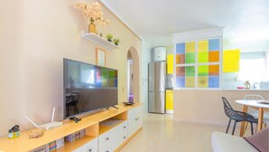 A modern kitchen with a large TV, a refrigerator, and a colorful window.