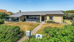 Ein modernes Haus mit Satteldach, großen Fenstern und einer Ziegelaußenwand.
