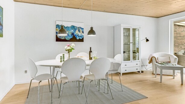 Un espace de salle à manger moderne avec une table blanche, des chaises et un meuble vitré.
