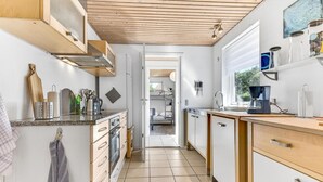 Une cuisine compacte avec un plafond en bois, un four encastré et une machine à café.