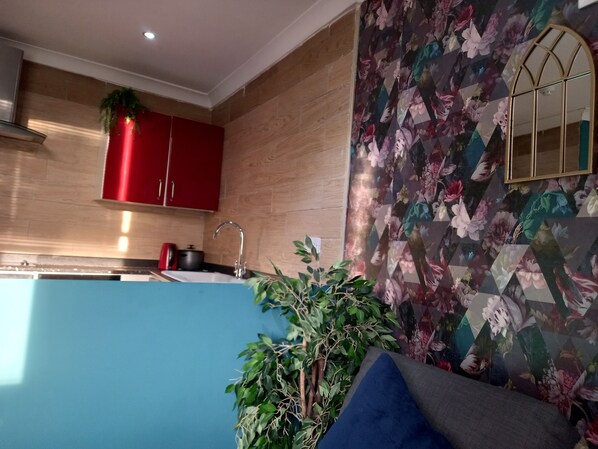 Une cuisine moderne avec des meubles de rangement en bois, un meuble rouge, un évier et une cuisinière.