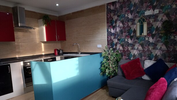 A modern kitchen with a central island, a built-in oven, and a red cabinet. - Stockton Moors (Stockton-on-Tees)