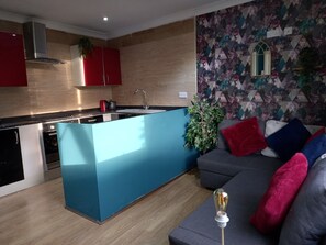 Une cuisine moderne dotée d’un îlot central, d’un four encastré et d’un meuble rouge.