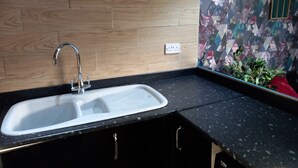 A kitchen with a double sink, wooden backsplash, and a floral-patterned wall. - Stockton Moors (Stockton-on-Tees)