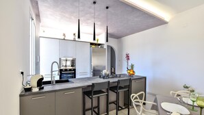 A modern kitchen with a central island, stainless steel appliances, and a dining area with white chairs. - Lovely home in Balestrate (Balestrate)