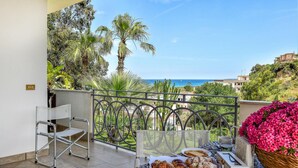A balcony with a table set for breakfast, overlooking a coastal landscape with palm trees and a view of the sea. - Lovely home in Balestrate (Balestrate)