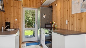 A compact kitchen with wooden walls, a stainless steel sink, and a refrigerator.