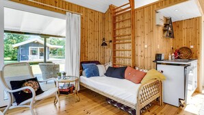 A cozy room with a bed, a small table, and a chair. There's a window with a view of a house outside.