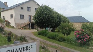 Señal para 'CHAMBRES D'HÔTES GÎTES Le Domaine de Moise' que indica un entorno hotelero con un edificio de piedra, una escalera y abundante vegetación.