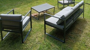 Un área de estar al aire libre con mobiliario moderno, una pequeña mesa y un banco.