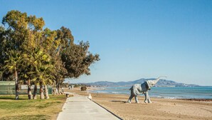 A coastal walkway with a concrete path, palm trees, and a large elephant statue. - Gorgeous apartment in Oropesa del Mar with sauna (Oropesa del Mar)