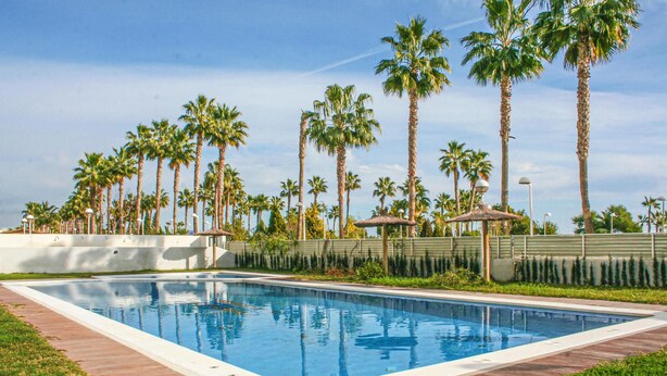 A rectangular swimming pool with a wooden deck surrounding it, bordered by a low wall. - Gorgeous apartment in Oropesa del Mar with sauna (Oropesa del Mar)